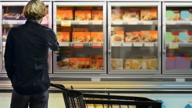 Image d'une personne devant un réfrigérateur d'épicerie